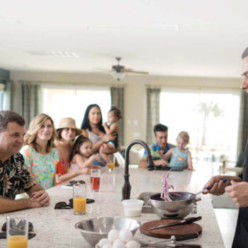 Family watches an expert chef cook in their Encore Resort home.