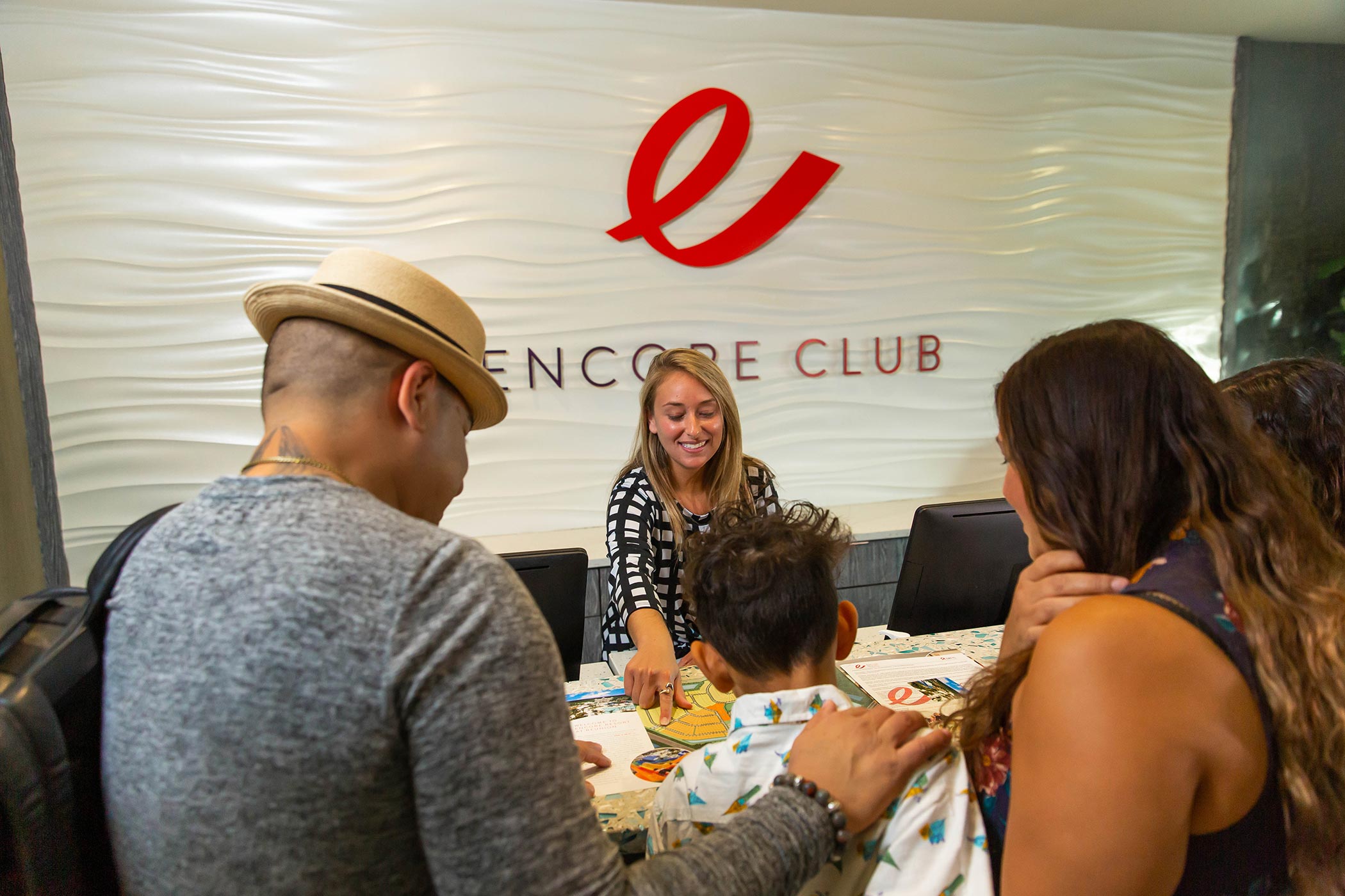 A member of the Encore Resort Concierge Team shows a family of guests points of interest on a resort map.
