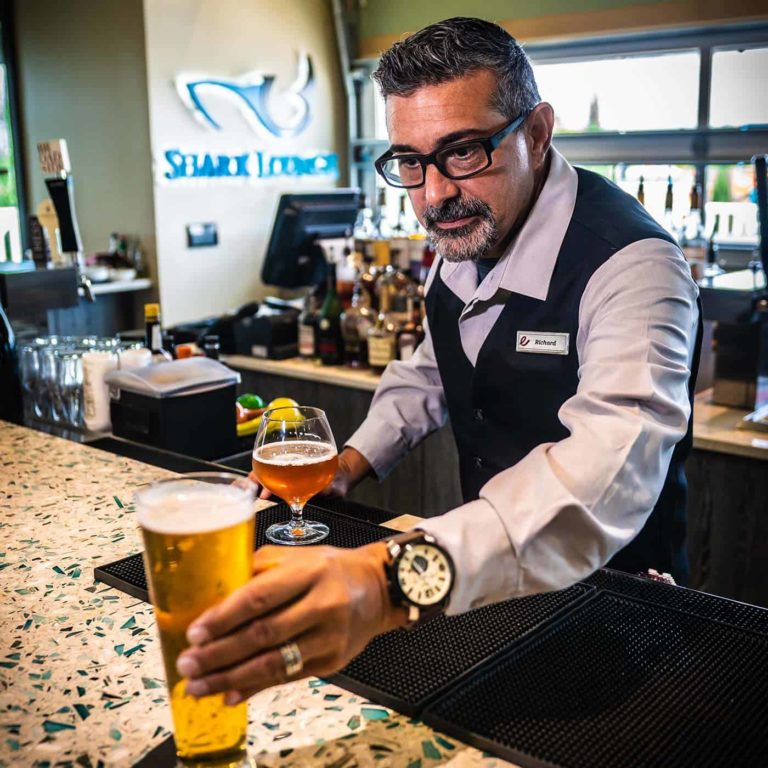 Ein Barkeeper serviert ein Bier an Shark Lounge.