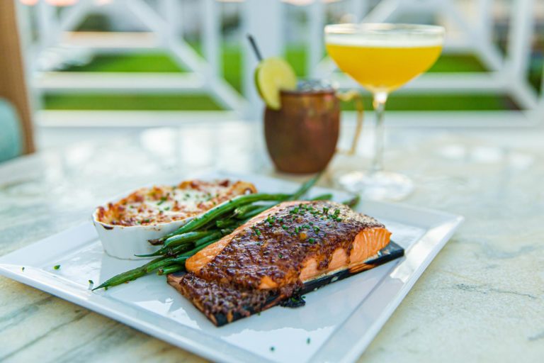 A plate of salmon with green beans and a drink.