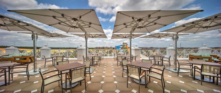 Covered seating areas on the Encore Resort Clubhouse outdoor deck, with a view of the water park slides in the distance.