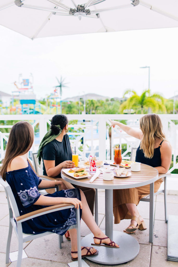 तीन महिलाएं एक साथ बैठकर खाना खा रही हैं Encore रिज़ॉर्ट क्लबहाउस की बाहरी छत।
