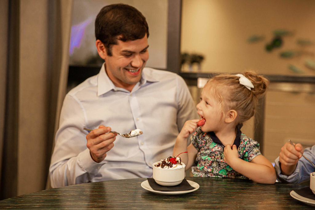 Ein Vater und eine Tochter teilen sich einen Eisbecher in einem Encore Ferienhausvermietung im Resort.