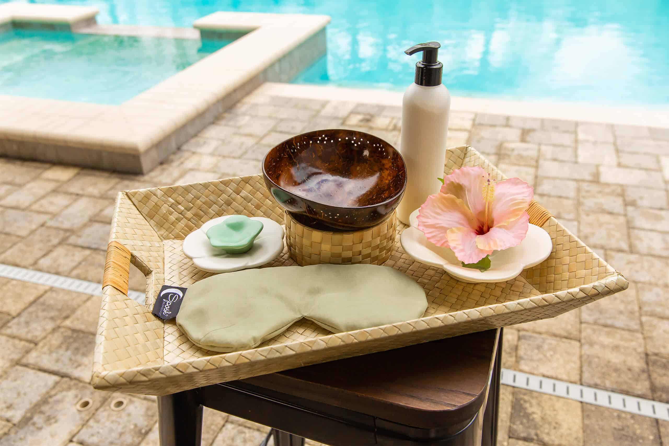 A face mask and other spa treatment essentials set on a table beside a private pool at an Encore Resort vacation home rental.