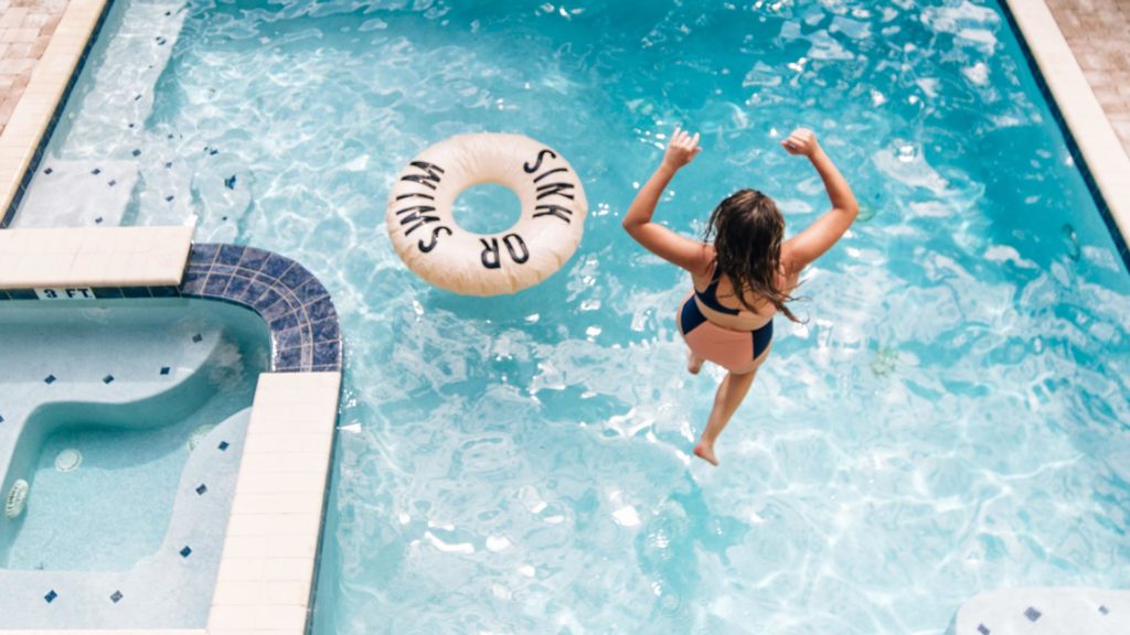 La femme saute dans une piscine privée à un Encore Location de maison de villégiature.