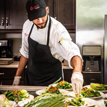 An Encore Resort expert chef garnishes plates of salad.