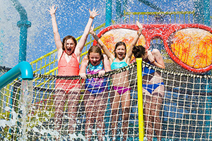 Kids cheering while being splashed with water in the Encore Resort Water Park’s Surfing Safari play area.