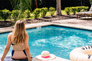 Frau sitzt am Pool in einer privaten Resortresidenz.