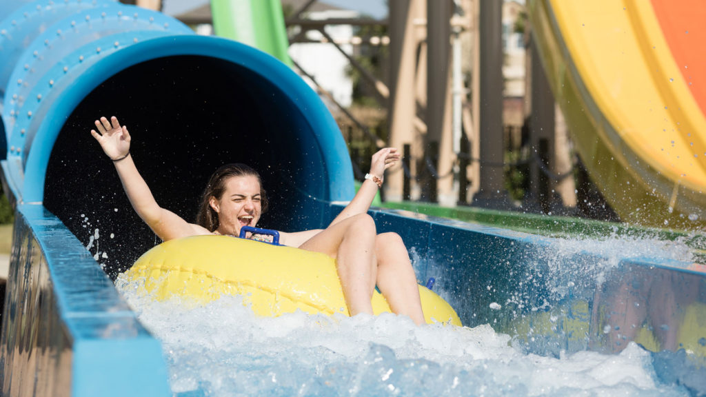 लड़की सुनामी वॉटर स्लाइड पर सवारी करती है Encore रीयूनियन के जल पार्क में रिज़ॉर्ट।