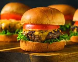 Set of slider cheeseburgers with lettuce and tomatoes.
