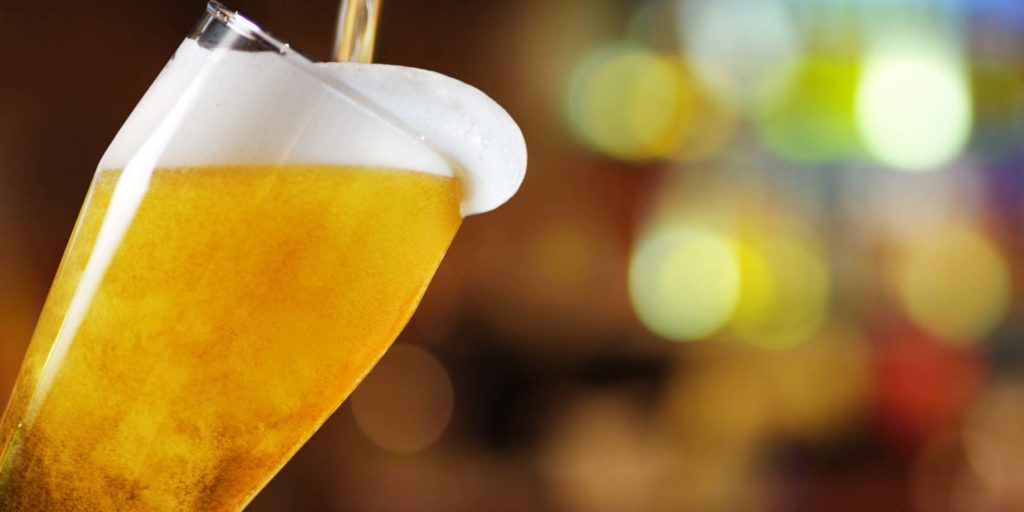 Cerveja sendo servida em um copo alto.