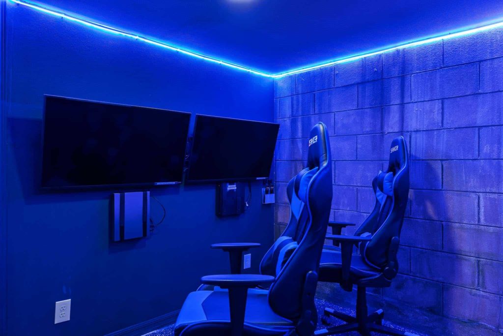 Dual TVs and gaming chairs in the stylish arcade room in Weathers’ Orlando vacation home.