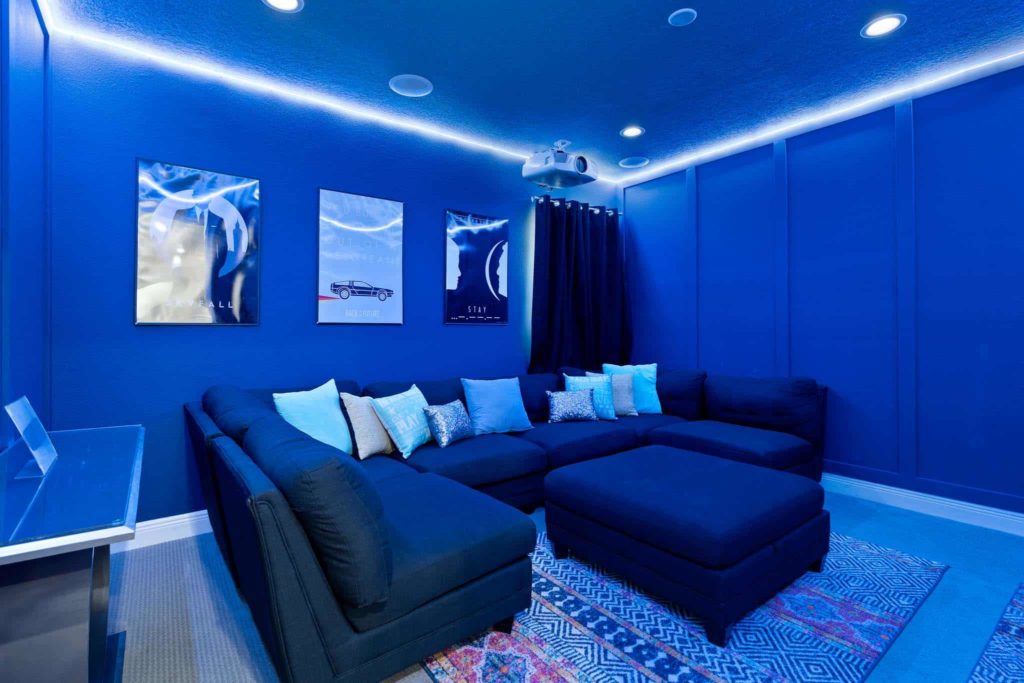 Home theater room with wrap-around couch and movie posters in Weathers’ Orlando vacation home.