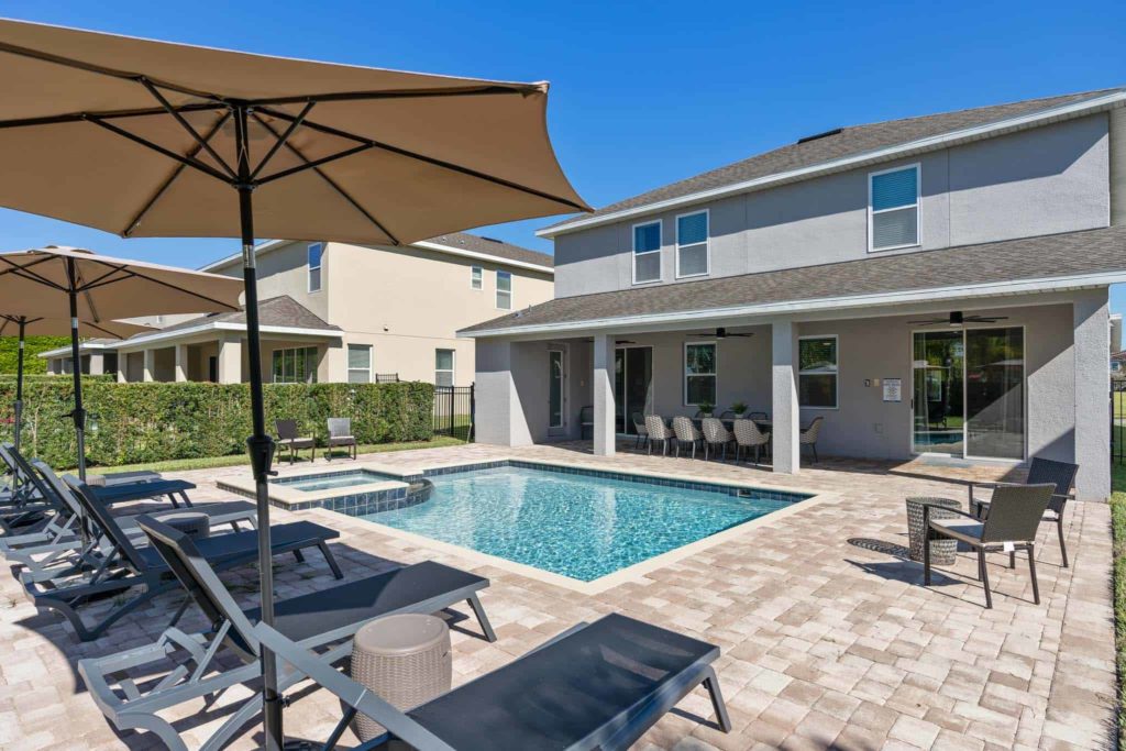 Private backyard pool surrounded by lounge chairs and umbrellas at Weathers’ Orlando vacation home.