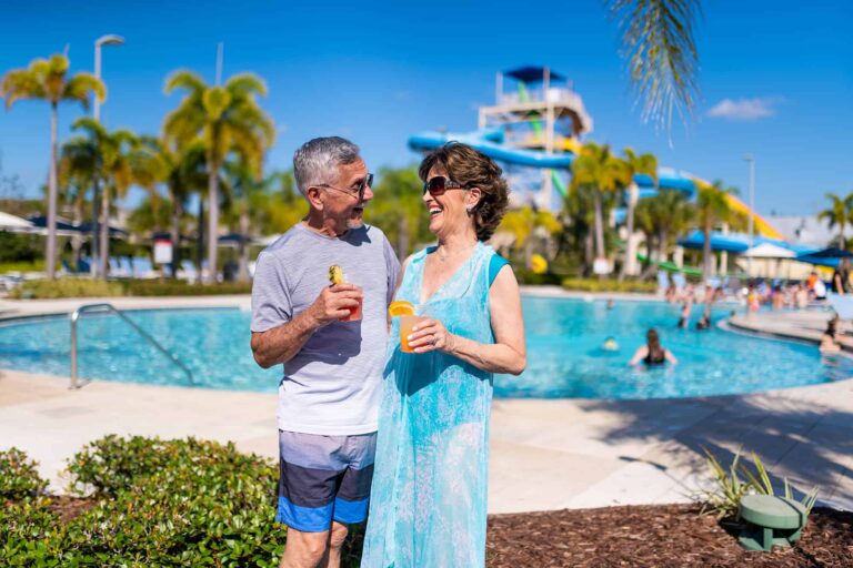 Paar steht mit Getränken daneben Encore Pool im Resort-Wasserpark