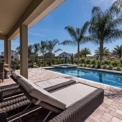 Private resort home backyard with sun loungers, covered lanai, pool, and Jacuzzi