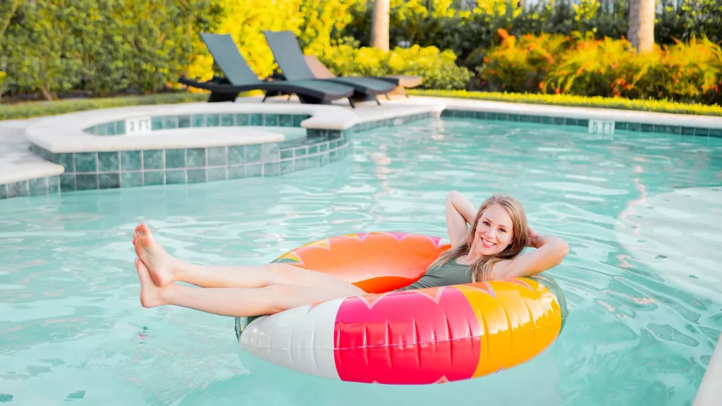 Woman smiling and relaxing in a tube float in a private resort home pool.