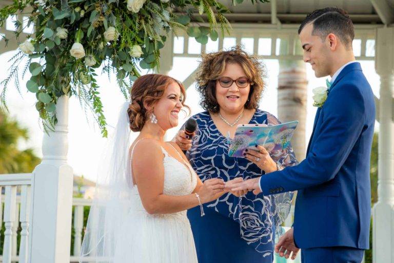 Жених и невеста обмениваются кольцами во время свадьбы под Encore Курортная свадебная беседка