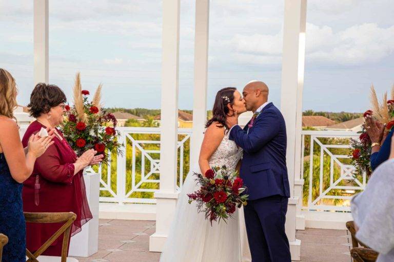 Les mariés s'embrassent à la fin de leur cérémonie de mariage le Encore Terrasse du clubhouse du complexe