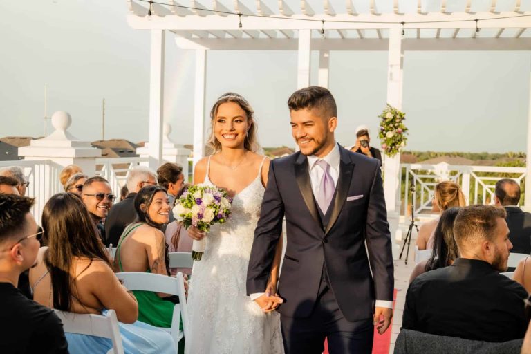 العروس والعريس يسيران في الممر في حفل زفافهما في Encore تراس المنتجع