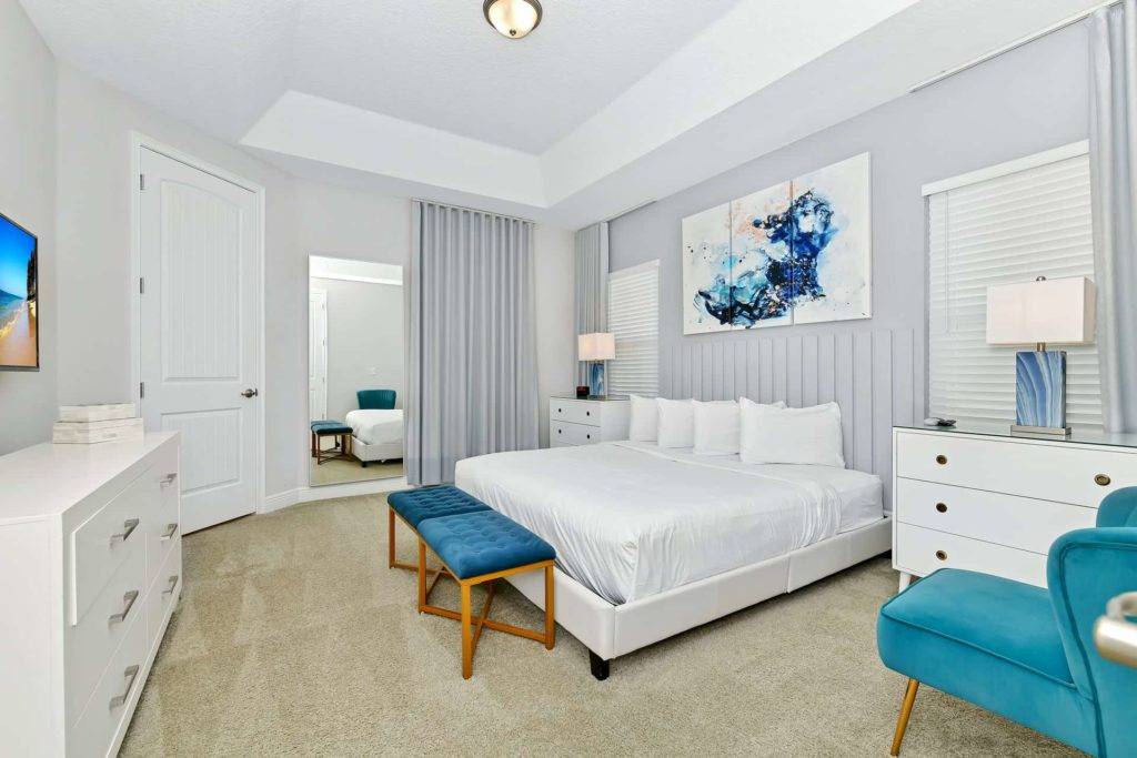 Master bedroom with large king bed, ottoman, and wall-mounted TV