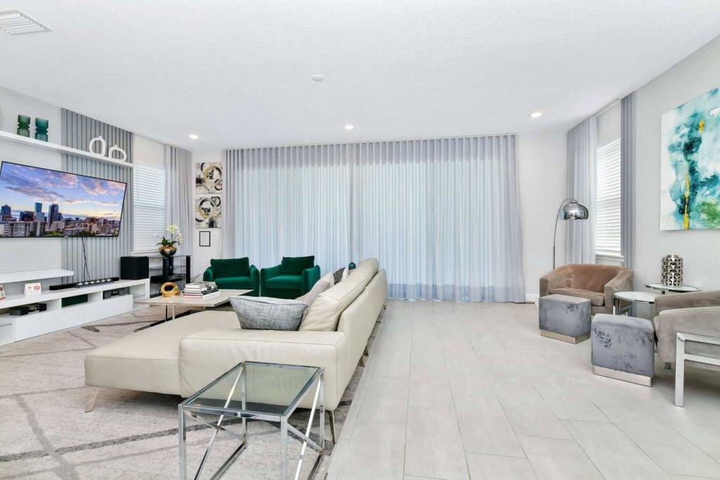 Living room with sofa, end tables, armchairs, and sliding door to outdoor lanai
