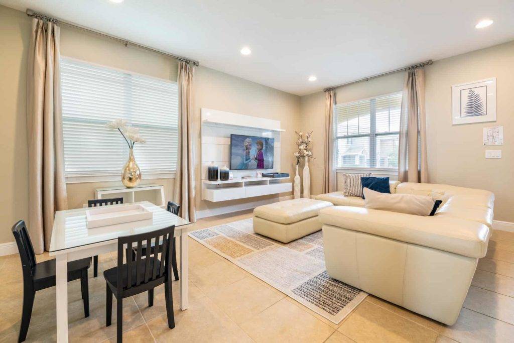 Spacious great room with sectional sofa, game table, ottoman, and wall-mounted TV