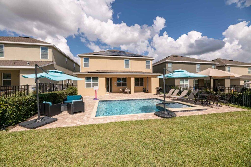 Backyard private pool with sun umbrellas, loungers, and tables
