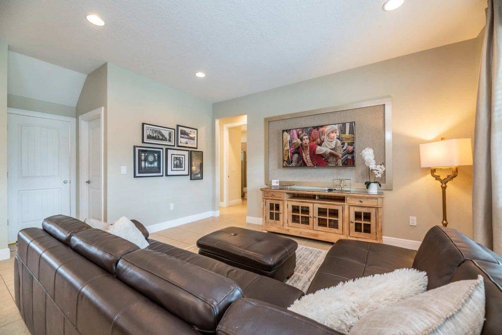 Living room with sectional sofa, ottoman, and wall-mounted TV