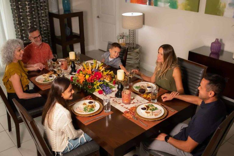 Family sitting together for Thanksgiving dinner in an Encore Resort vacation home