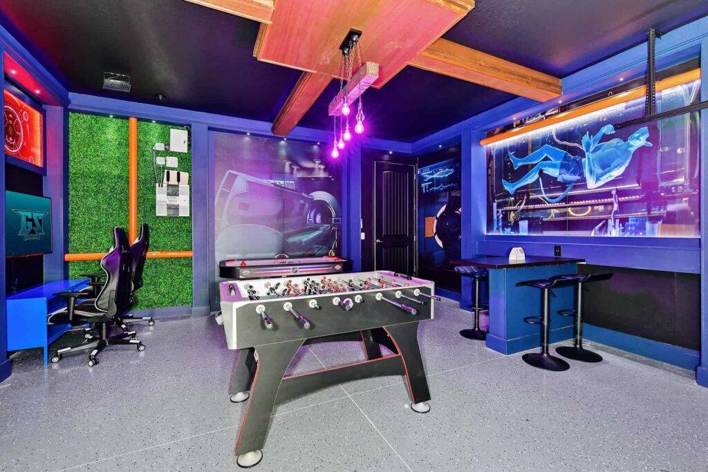 غرفة ألعاب مع لوحات جدارية ذات طابع مستقبلي وطاولات كرة قدم للهوكي الهوائي ومقاعد للبار