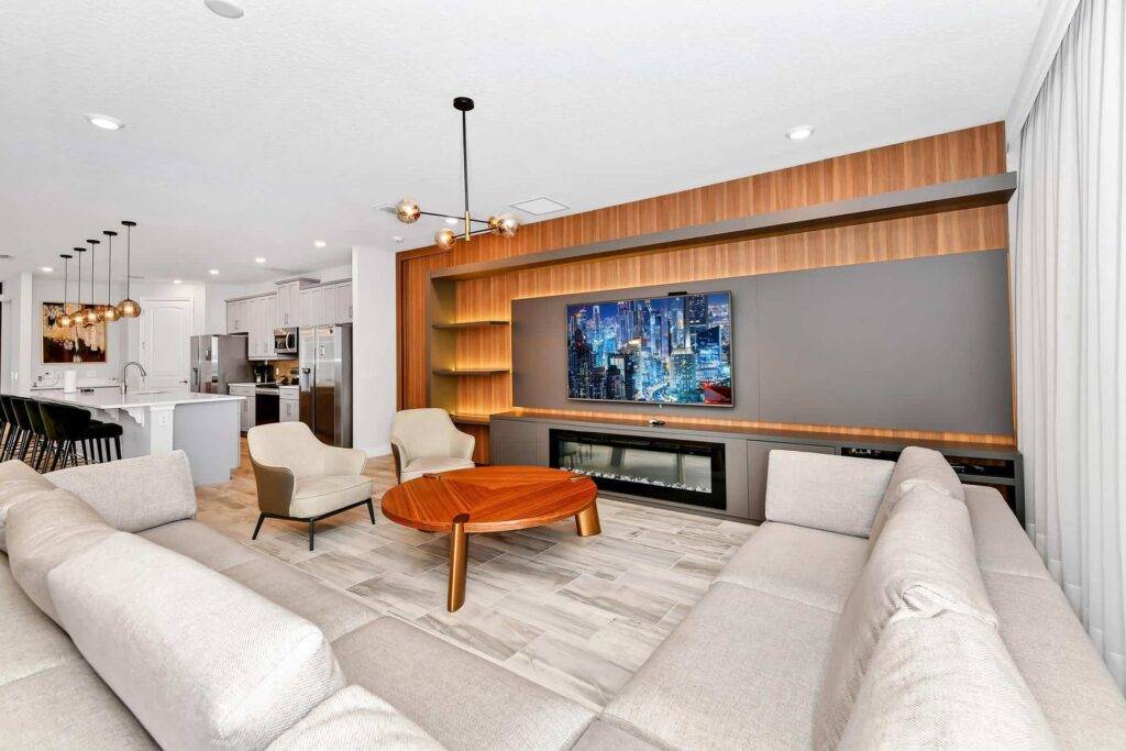 أريكة مقطعية ملفوفة في غرفة المعيشة مع تلفزيون مثبت على الحائط