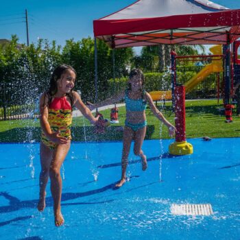 Two young girls playing in the water on the splash pad at Encore Resort’s East Side Amenity Center.