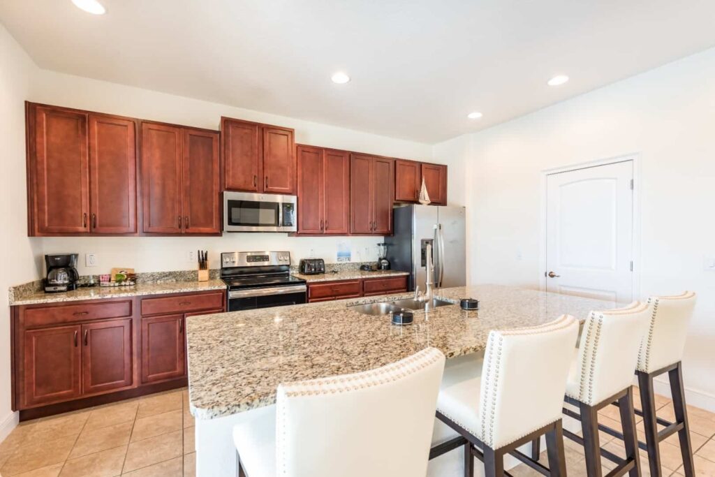 Fully equipped kitchen with large island counter featuring sink and barstool seating: 5 Bedroom Vacation Home