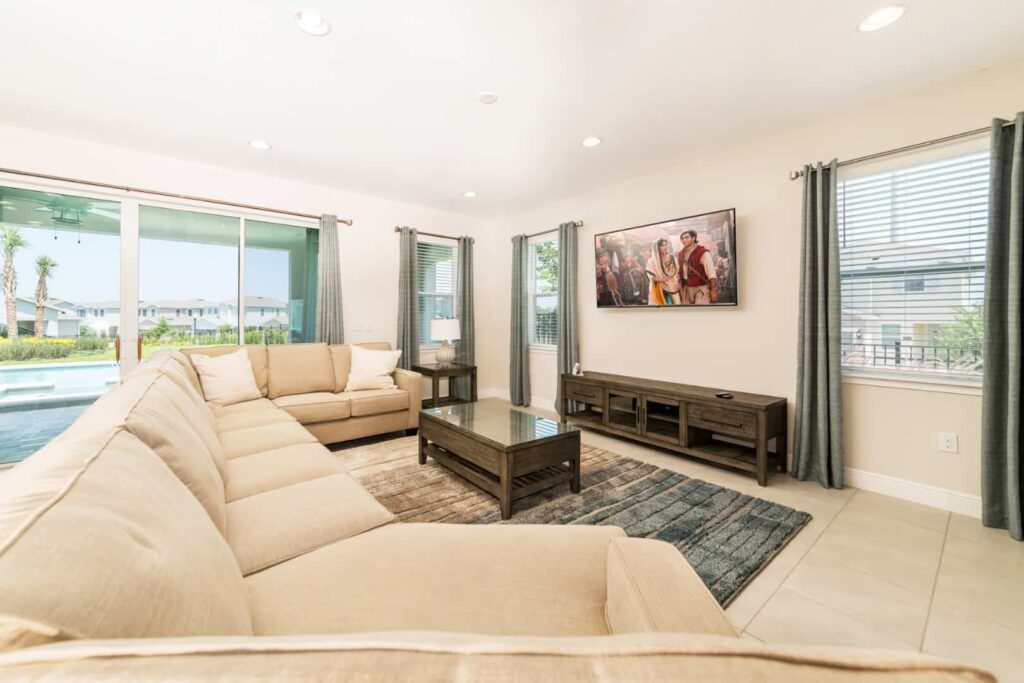Living room with large, wrap-around sectional sofa and wall-mounted TV: 5 Bedroom Vacation Home