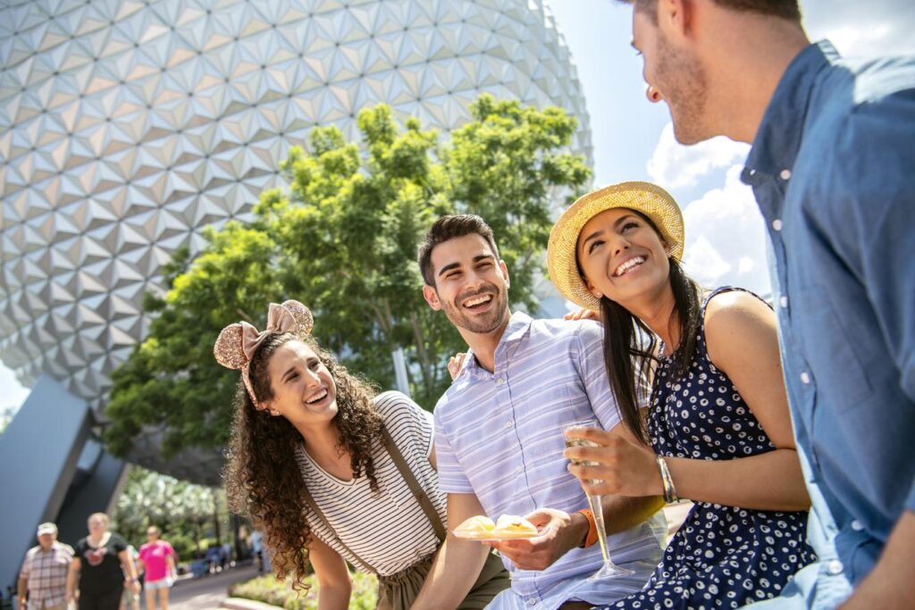 Две пары делят еду и вино в тематическом парке Epcot в Walt Disney World.