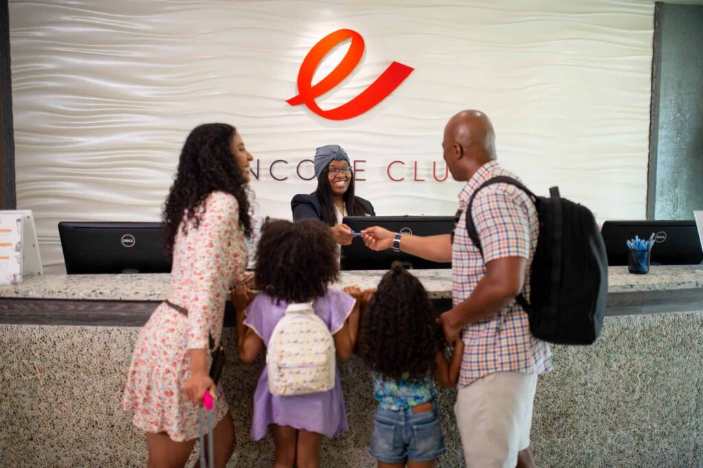 Família com dois filhos pequenos fazendo check-in com um Encore concierge do resort