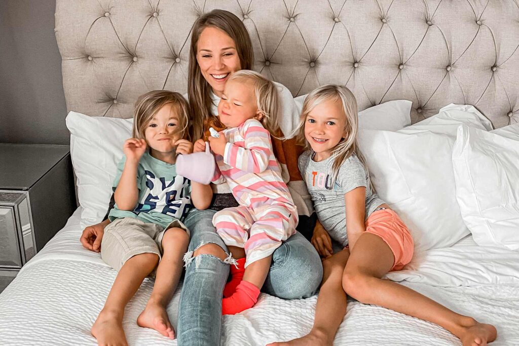 Mother resting in bed with her 3 kids at her Encore Resort home