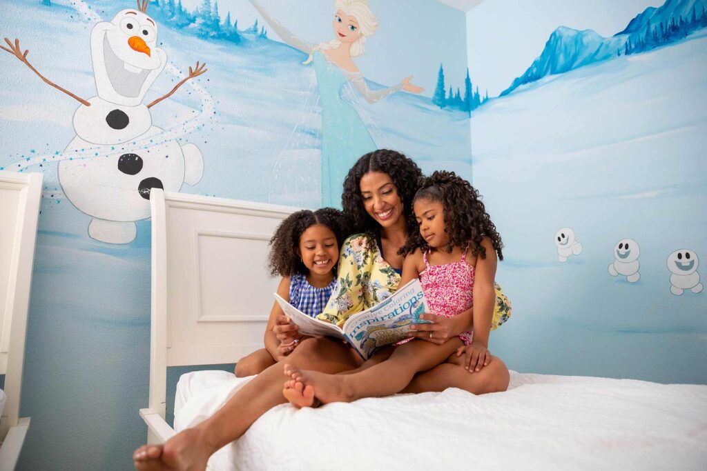 Mother reading a book to her daughters in a Disney's Frozen theme bedroom at their Encore Resort home.