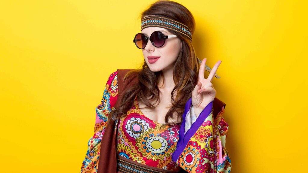 Frau in einem Hippie-Kostüm macht ein Friedenszeichen