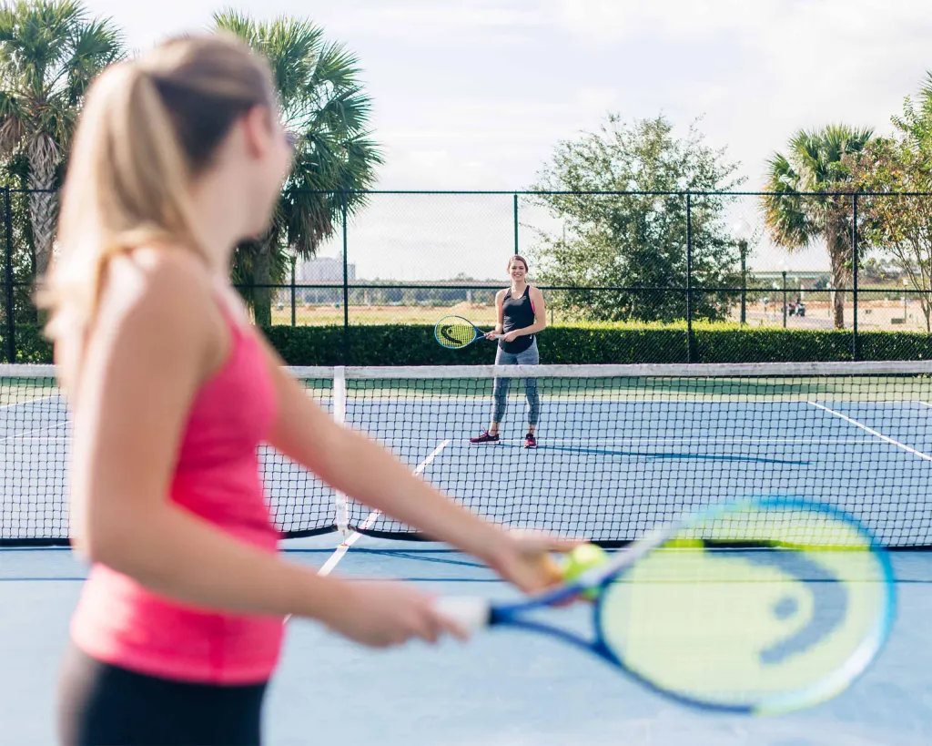 Women playing tennis on the Encore Resort East Side sports facilities.