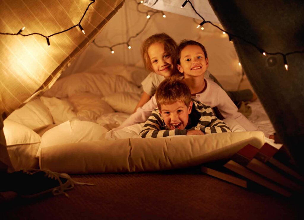 年幼的孩子们在毛毯堡垒中玩得开心