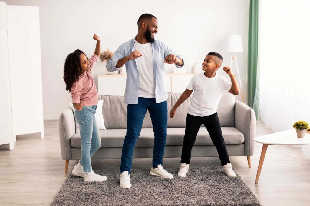 Vater und Kinder tanzen in ihrem Wohnzimmer zu Musik
