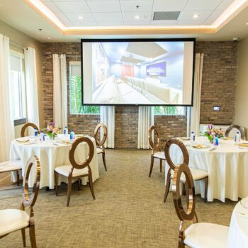 Tables and chairs set up for a private event with a projector image at the Encore Resort Clubhouse