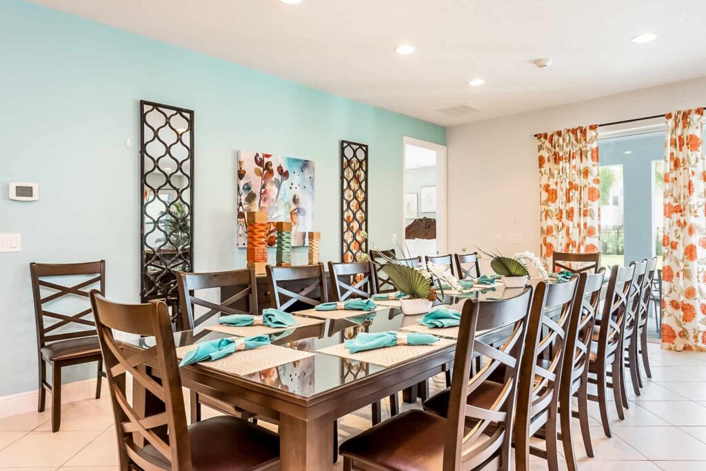 Dining room with glass-top table, cushioned seats, and sliding door to private backyard
