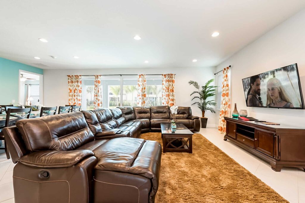 Living room with wrap-around sectional sofa, coffee table, TV, and sliding door to backyard