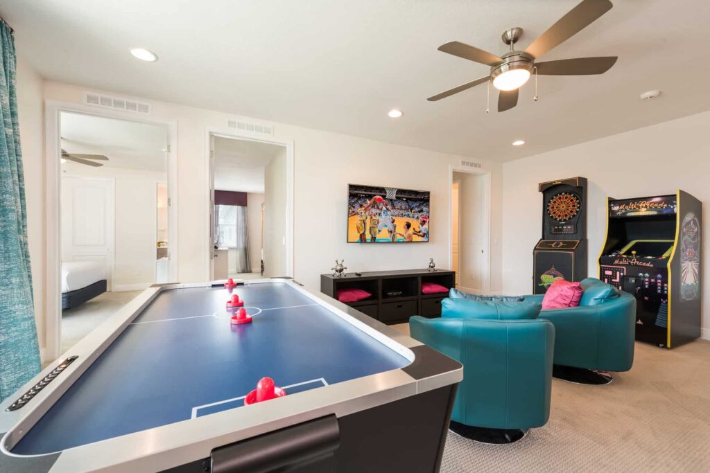 Game room with air hockey table, arcade cabinet, electronic dartboard, and wall-mounted TV