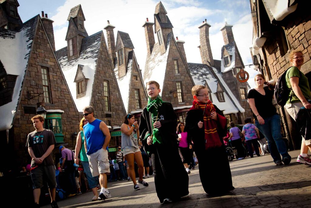 Crianças vestidas com trajes de Hogwarts andando pela vila de Hogsmeade no Universal Islands of Adventure