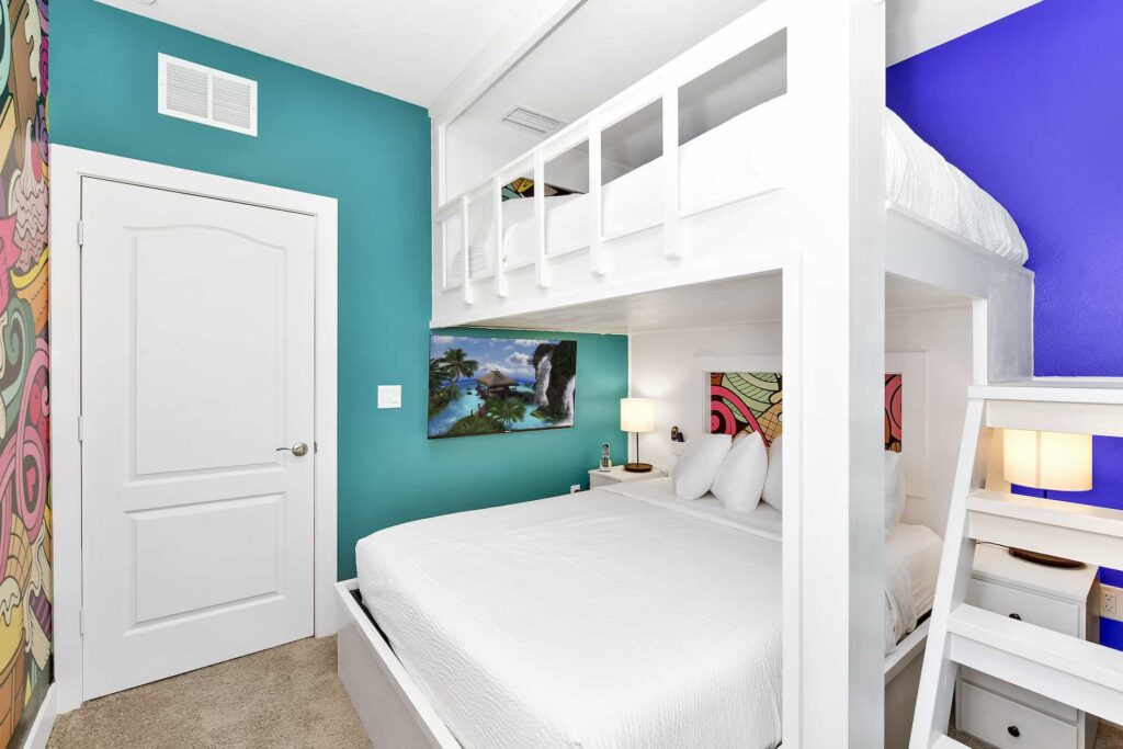 غرفة نوم 3 في منزل مكون من 4 غرف نوم في قرية ريونيون مع سرير كامل وسرير علوي فردي وسلّم متدرج وتلفزيون مثبت على الحائط