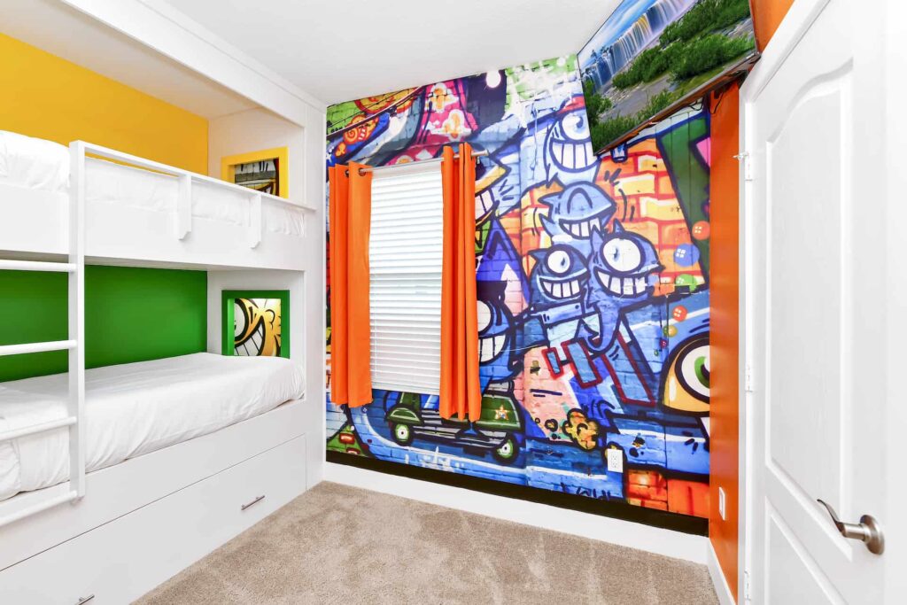 Schlafzimmer 4 im Reunion Village 4-Zimmer-Haus mit eingebauten Etagenbetten, farbenfrohen Wandgemälden und an der Wand montiertem Fernseher